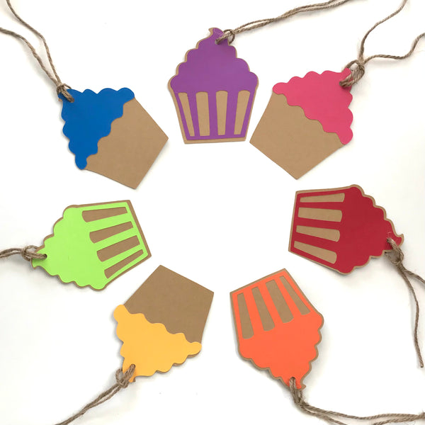 7 cupcake shaped gift tags are displayed in a circle.  Each tag is a different colour, from top clockwise they are: purple, pink, red, orange, yellow, green, and blue.