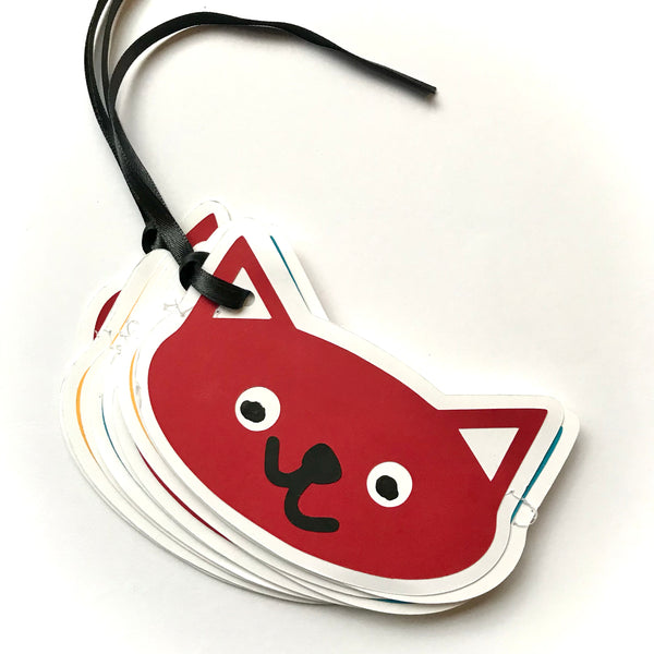 A cat head garland is shown careful bundled together against a white background.  There are black strings from the ends of the garlands displayed to the top left.  The showing cat face is red with a crooked nose and mouth.
