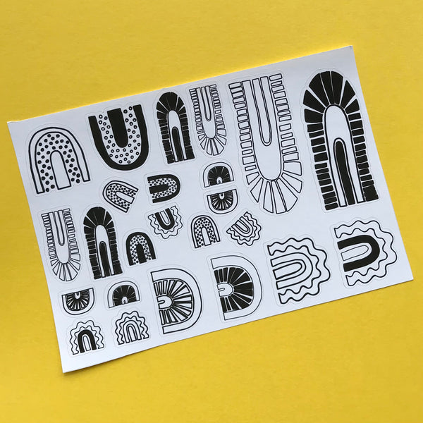 A single sheet of black and white rainbows is shown on a yellow background.  There are a total of 24 stickers in various sizes on the sheet.