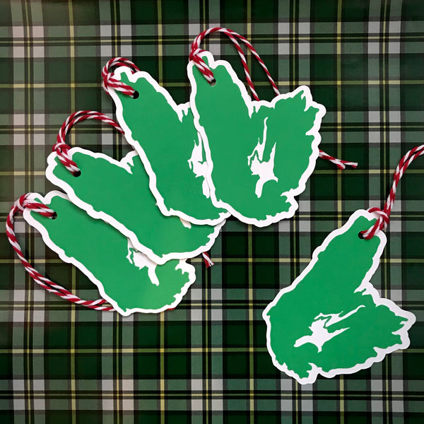 5 paper gift tags are shown against a background of the official Cape Breton Island Tartan.  Each gift tag is in the shape of Cape Breton Island.  4 gift tags are shown gently stacked together at the top left of the image, with a single gift tag towards the bottom right