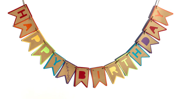 An adult humour banner that reads Happy Fucking Birthday is hung against a white background
