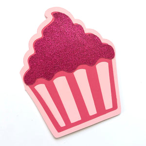 A cupcake shaped card in shades of pink is shown against a white background