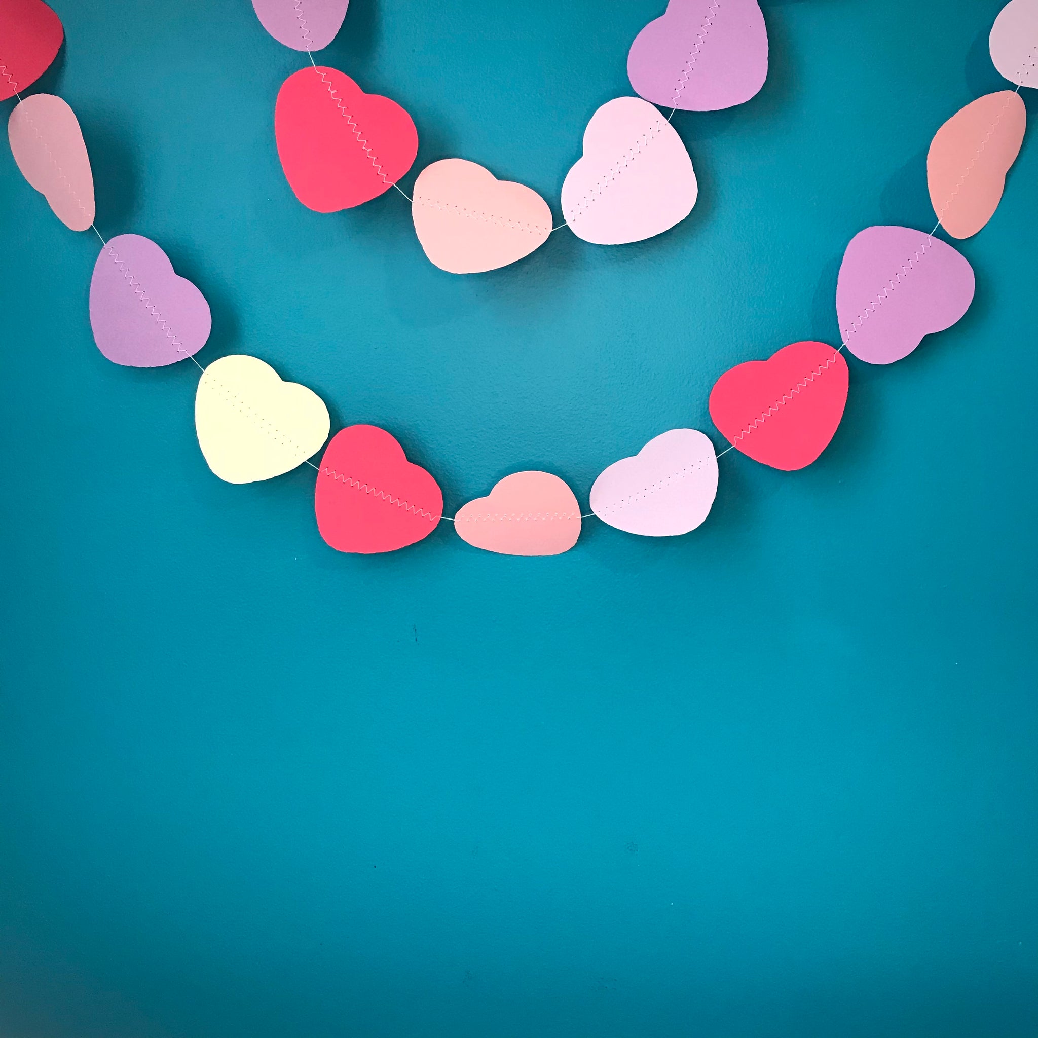 Two strings of pink and purple hearts are shown against a blue background