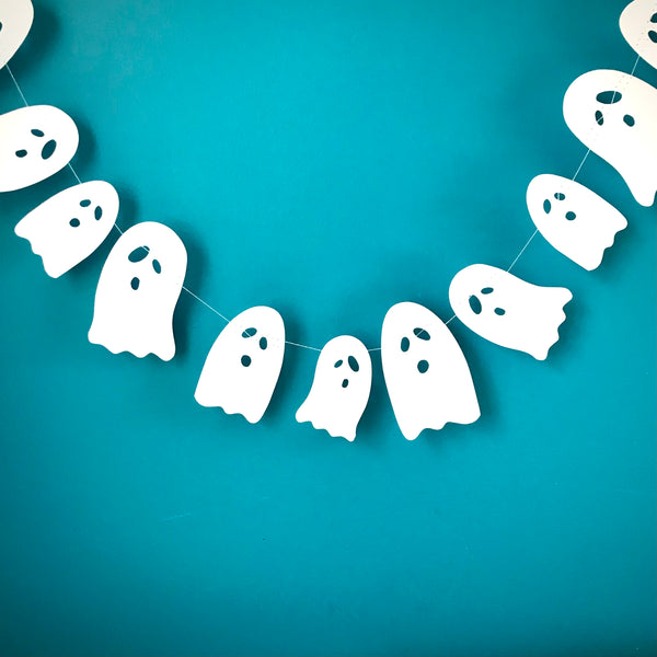 A sting of white ghosts form a little garland, hanging against a blue background
