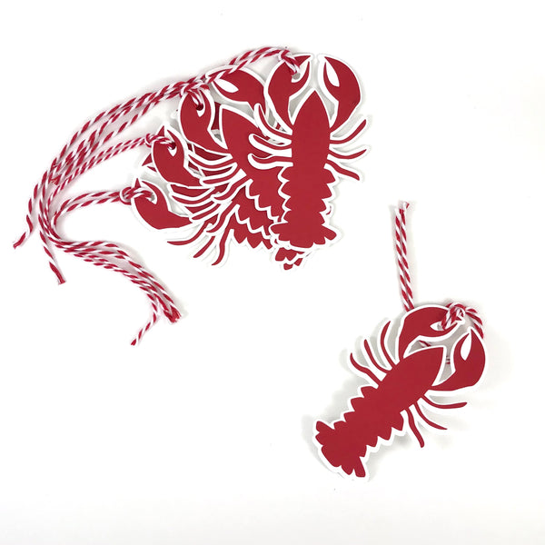 5 lobster gift tags are shown on a white background.  4 lobster are shown fanned out near the top left corner of the image, while a single lobster is at the bottom right corner of the image.  Each lobster is two layers of paper, white and red, with a red and white string attached to the left claw of each lobster