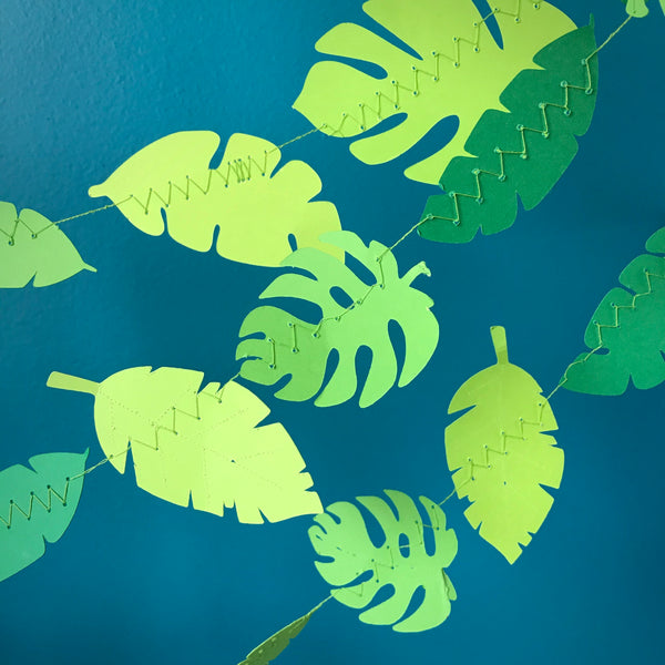 Three strings of green leaf garlands are hung from the top right corner to the bottom left corner, against a blue background.