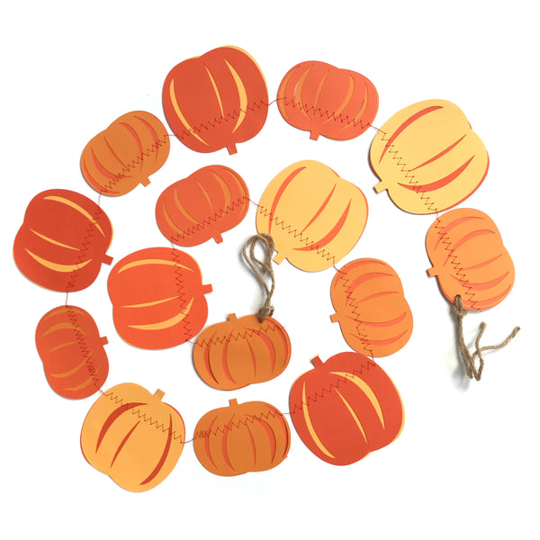 A string of 15 pumpkins are shown in a curl against a white background