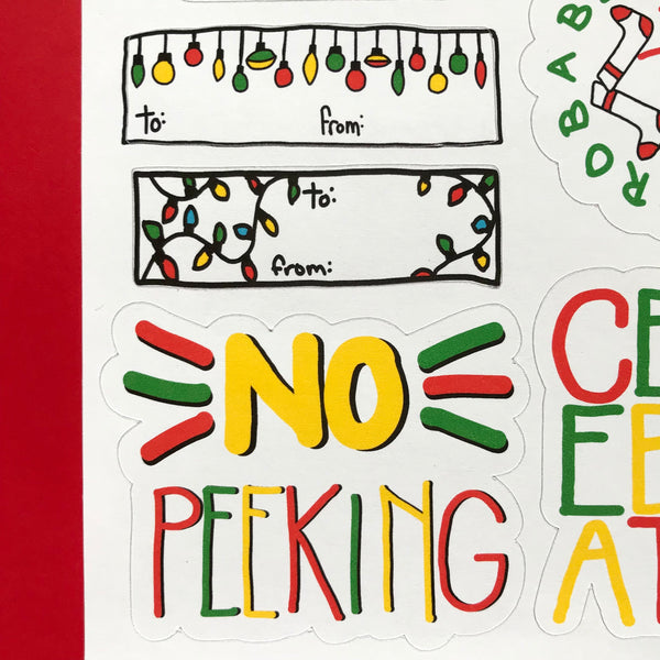 A close up image of three sticker tags. One is a rectangle with ornaments hanging from the top and a to and from across the bottom.  The Second is a rectangle with little christmas lights across the narrow ends and a to/from in the middle.  The third is a large NO PEEKING sticker.
