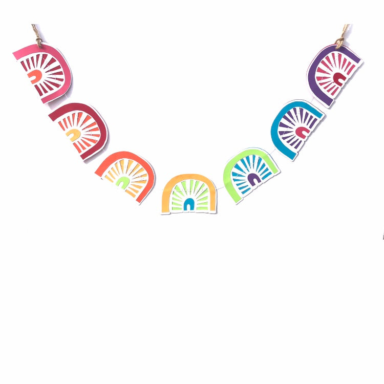 a paper garland of 7 little rainbows hangs against a white background.  