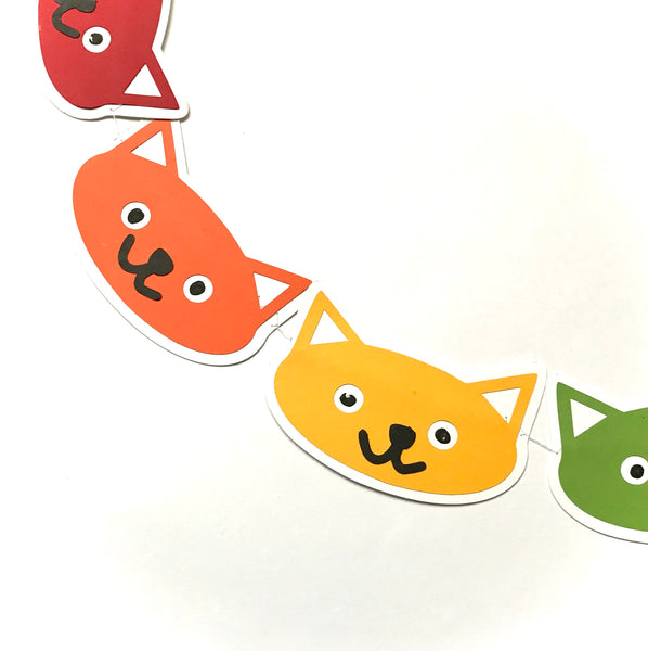 a portion of a cat head garland is shown against a white background.  The cat heads are red, orange, yellow and green