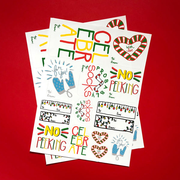 two sheets of festive sticker tags are displayed against a red background.  Phrases like CELEBRATE, FOR YOU and WITH LOVE are seen, among others