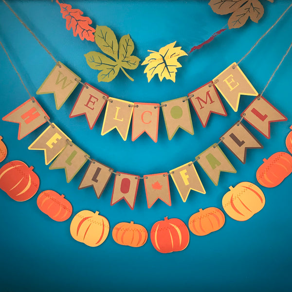 Four fall themed garlands and banners are hung against a blue background.  The top garland is of fall leaves, the second is a banner that reads Welcome, the third is a banner that reads Hello Fall and the final fourth one is a pumpkin garland